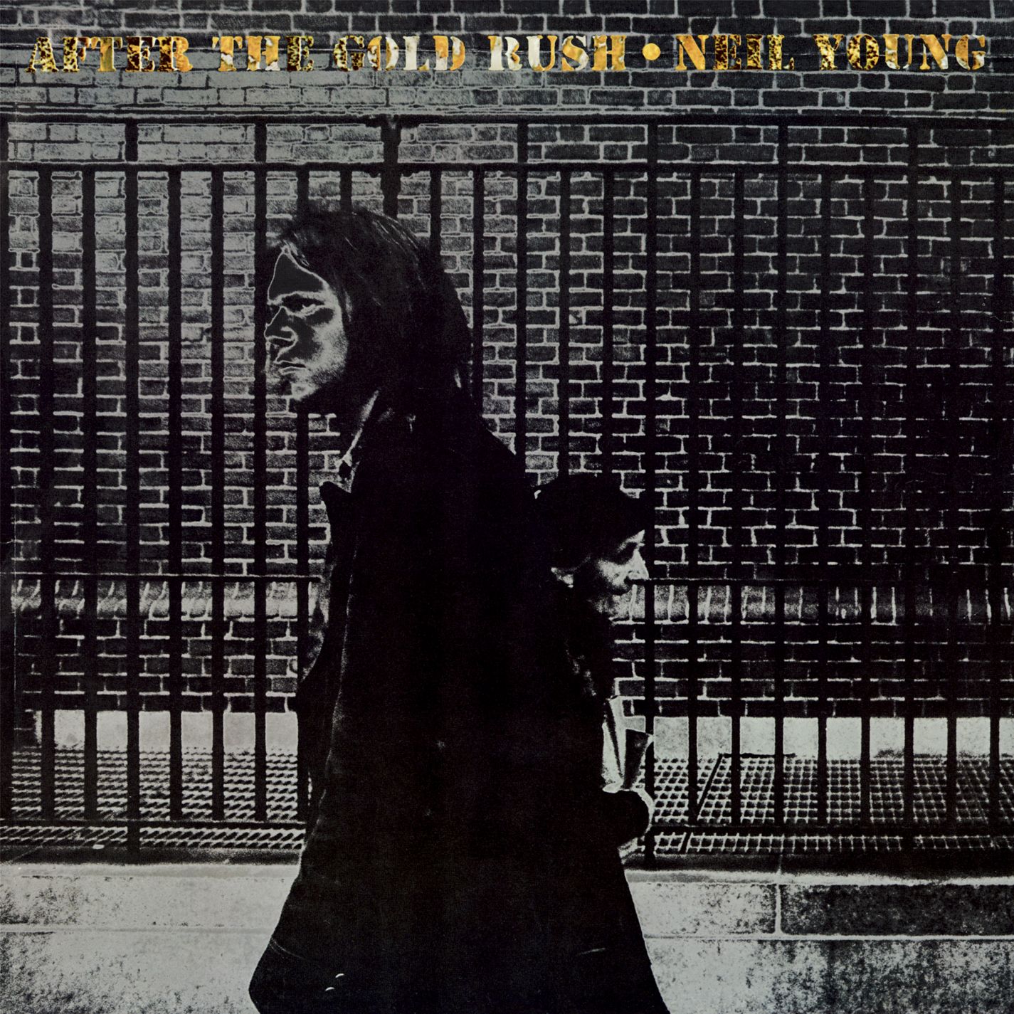The album cover for After the Gold Rush by Neil Young shows a black-and-white image of two people walking past a brick wall and iron fence, with the album title and artist’s name in yellow at the top.