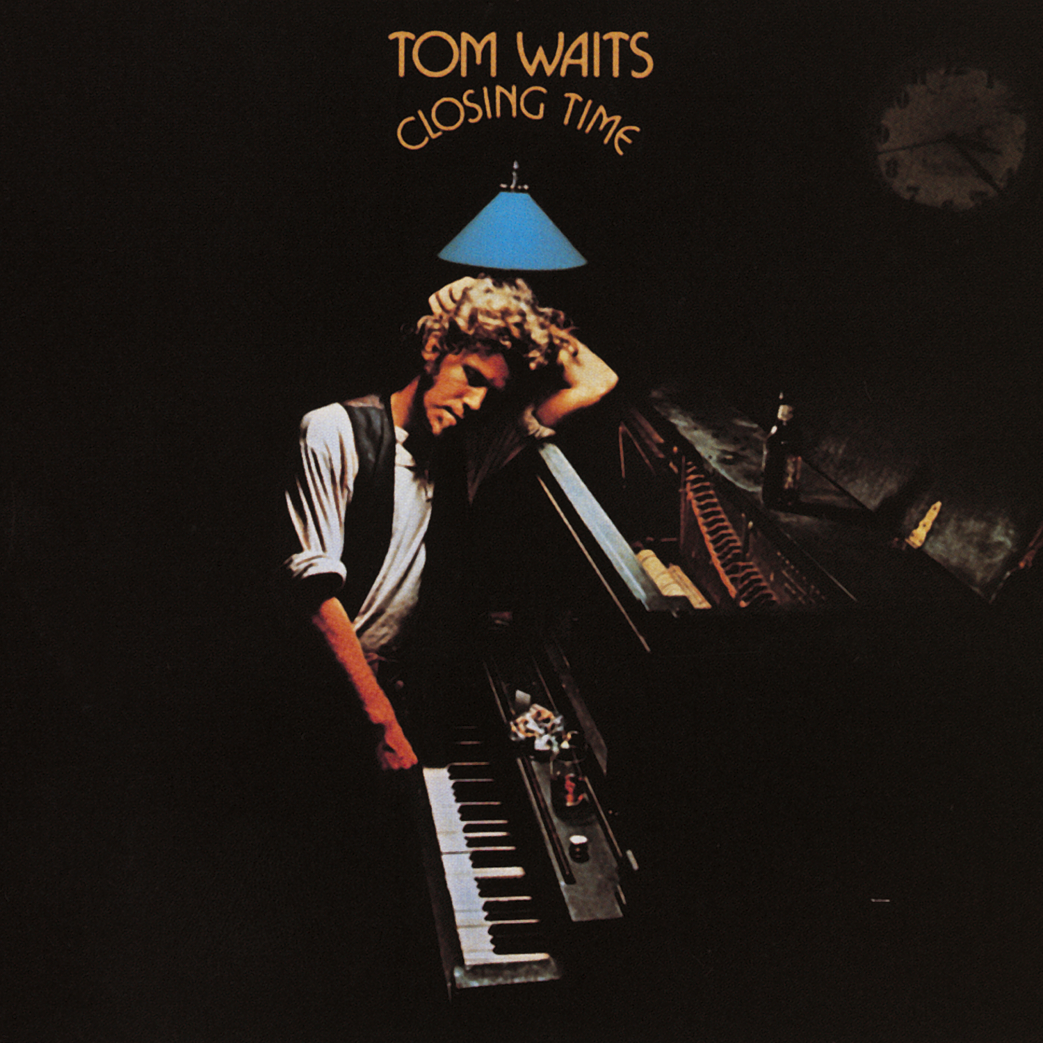 A man leans on a piano under a blue hanging lamp, with the words Tom Waits Closing Time above him in yellow text. The scene is dimly lit, creating a moody, intimate atmosphere.