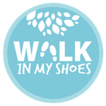 Light blue circular logo with white text reading WALK IN MY SHOES. The word WALK has two shoe prints in place of the letter A. Leaf shapes are arranged above the text.